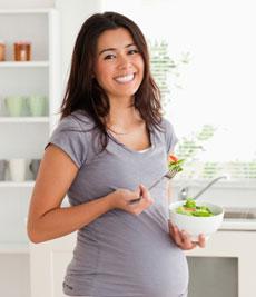 Femme enceinte souriante mange debout
